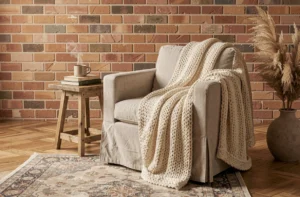 Coin salon cosy avec fauteuil en lin, plaid tricoté crème et table basse en bois brut dans une atmosphère chaleureuse et tendance